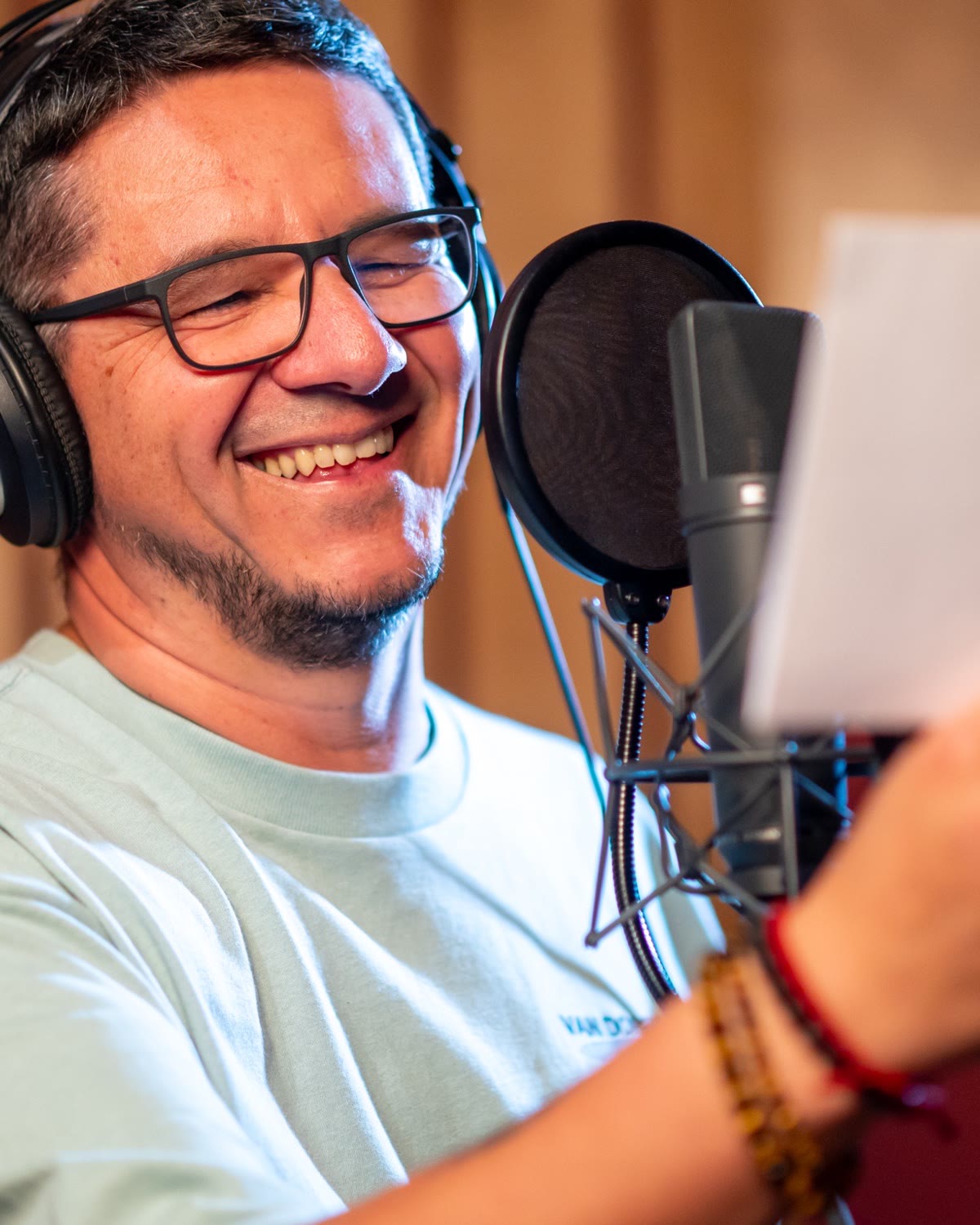 Markus Warscher mit Kopfhörern am Studiomikrofon bei einer Sprachaufnahme.